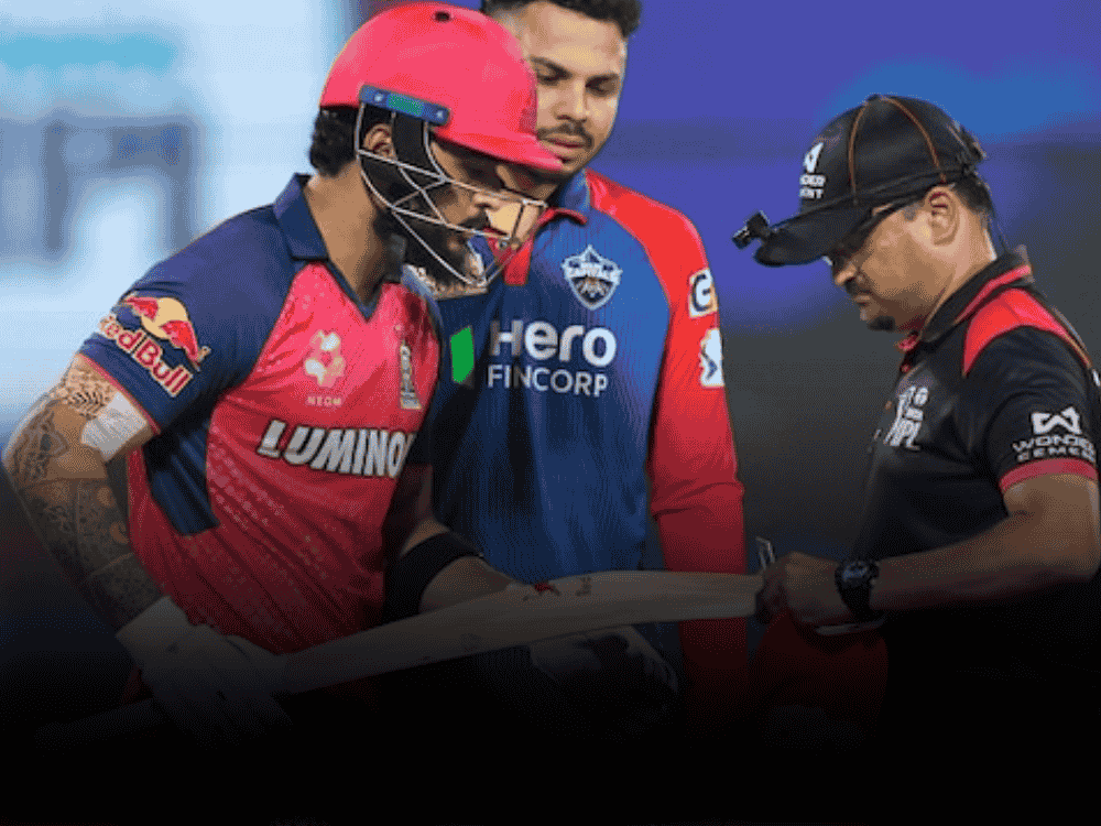 Umpire checking the bat of Rajasthan Royals player Riyan Parag during an IPL 2025 match, using a bat gauge to ensure it meets official size regulations.