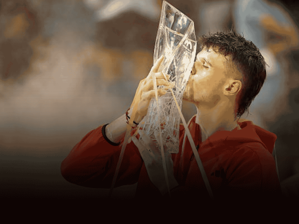 Jakub Menšík in orange hoodie kissing the Miami Open 2025 after defeading