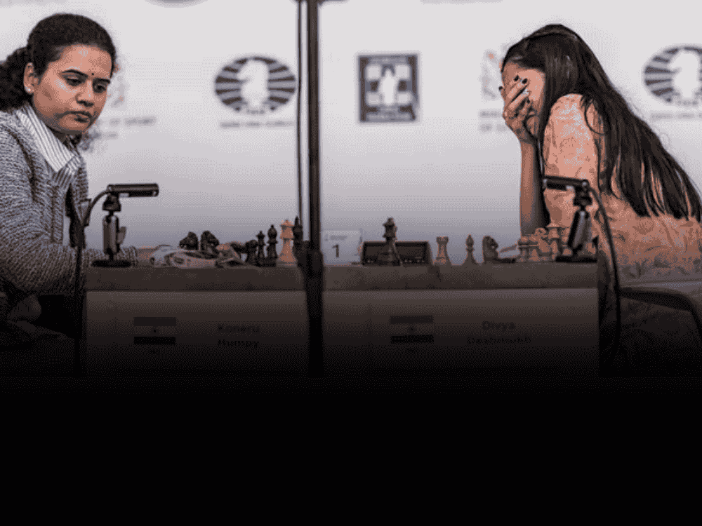 Divya Deshmukh (right) and Humpy Koneru (left) during the final match of FIDE Women’s World Cup 2025, with chessboard and clock in center.